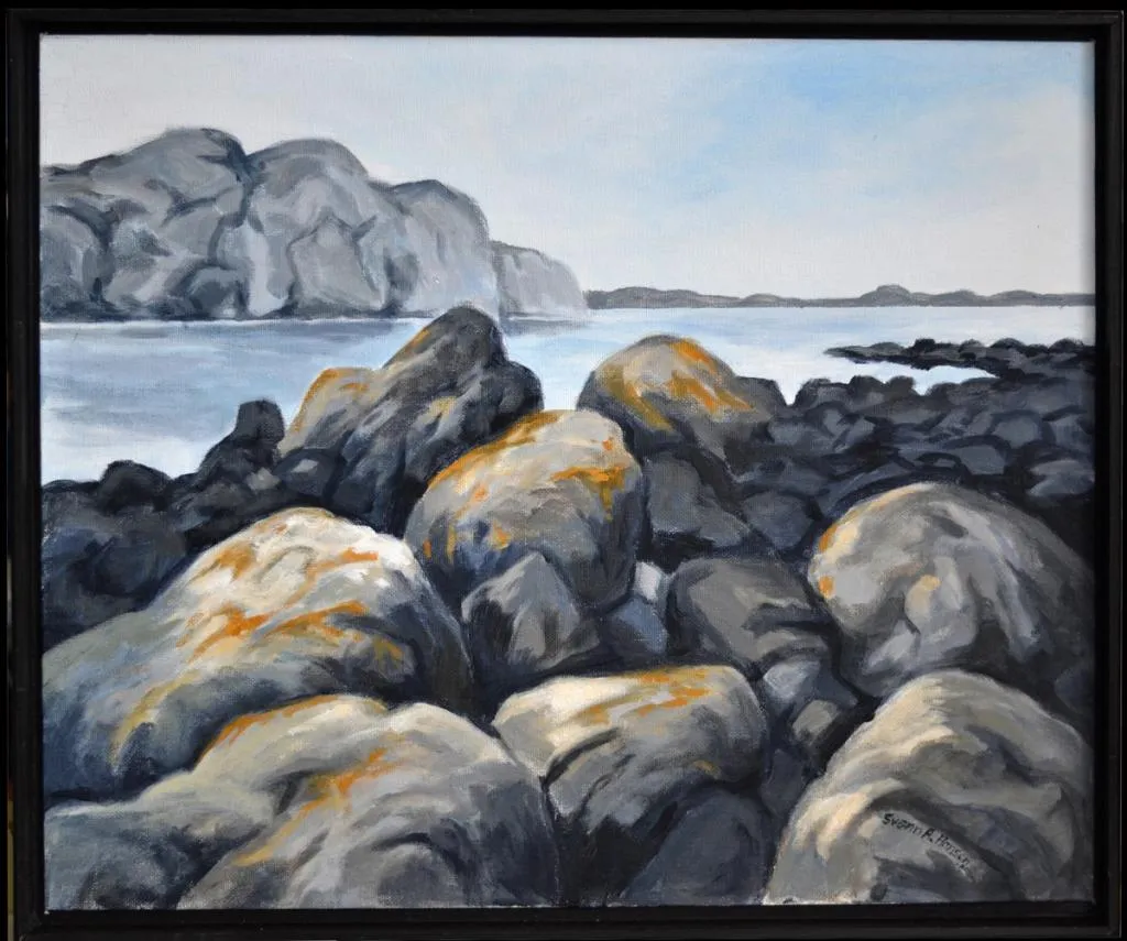 Store steiner ligger ved vannkanten og landskap i bakgrunnen